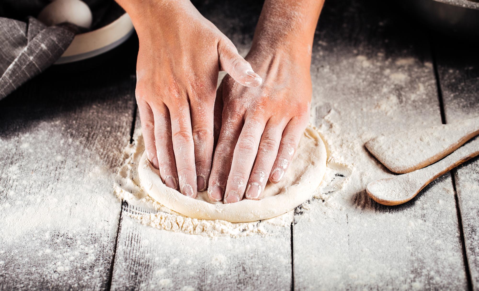 Hands shaping dough in a rustic kitchen